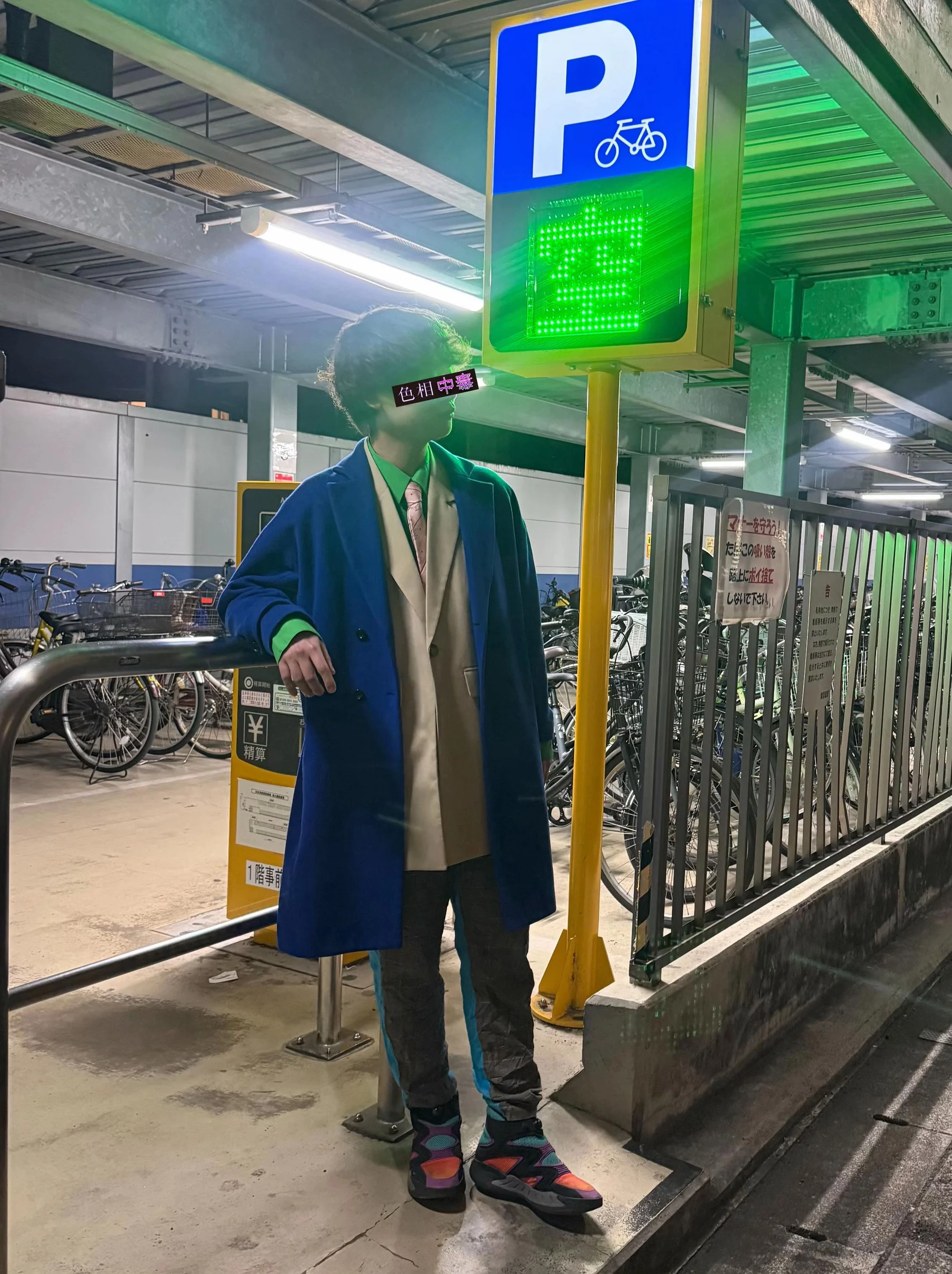 緑のネオンと黄色いポールのそばで、青いロングコート、緑のシャツ、ベージュのジレ、ピンクのネクタイを着た色相中毒者